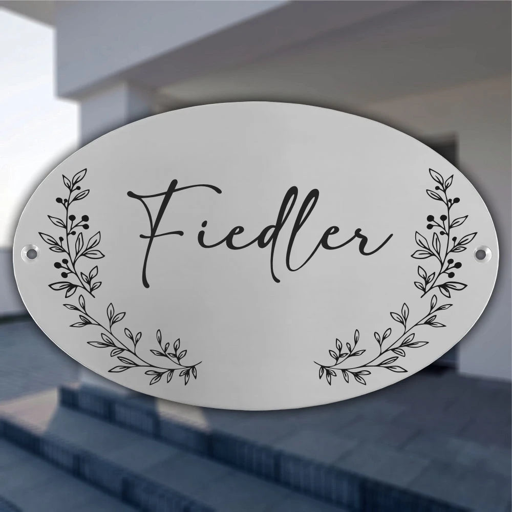 Ovales personalisiertes Türschild aus Edelstahl mit graviertem Familiennamen und floralen Ranken