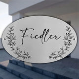 Ovales personalisiertes Türschild aus Edelstahl mit graviertem Familiennamen und floralen Ranken