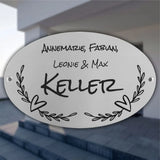 Personalisiertes ovales Türschild aus Edelstahl mit Familienname, Vornamen, Herzmotiv und floralen Ranken