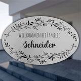 Personalisiertes ovales Türschild aus Edelstahl mit individuellem Wunschtext und floralen Verzierungen